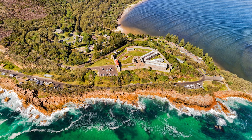 An aerial view of a coastal area with a beach, a large building complex, and a rocky coastline.