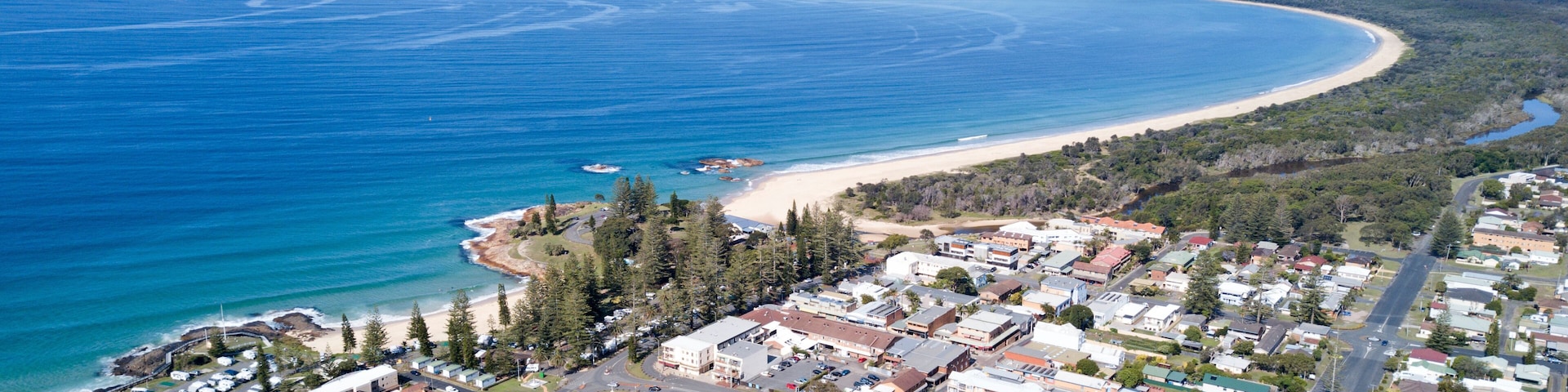 A coastal town with a beach, dense forest, and a marina.