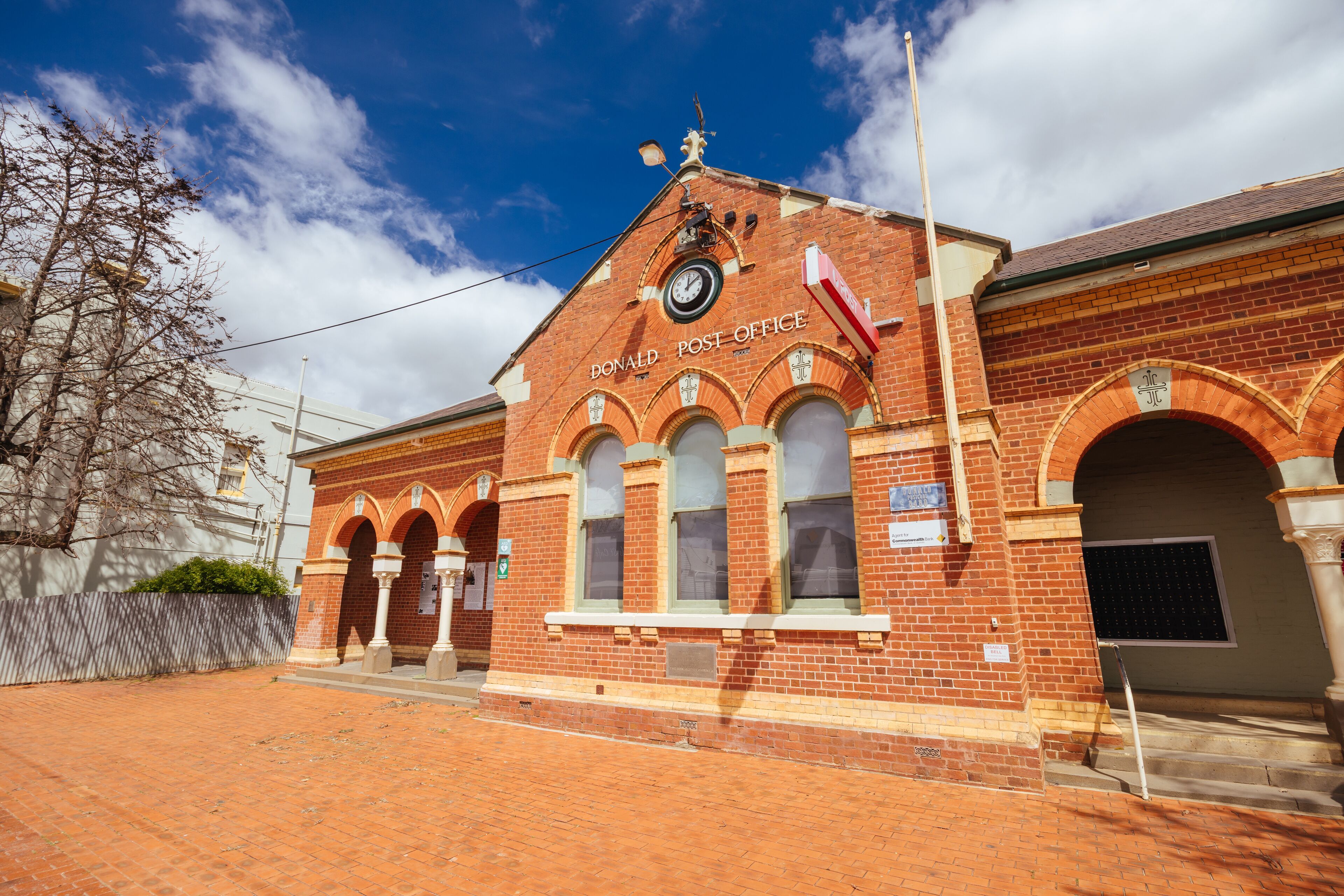 A brick building with arched windows and a clock, labeled "Donald Post Office."