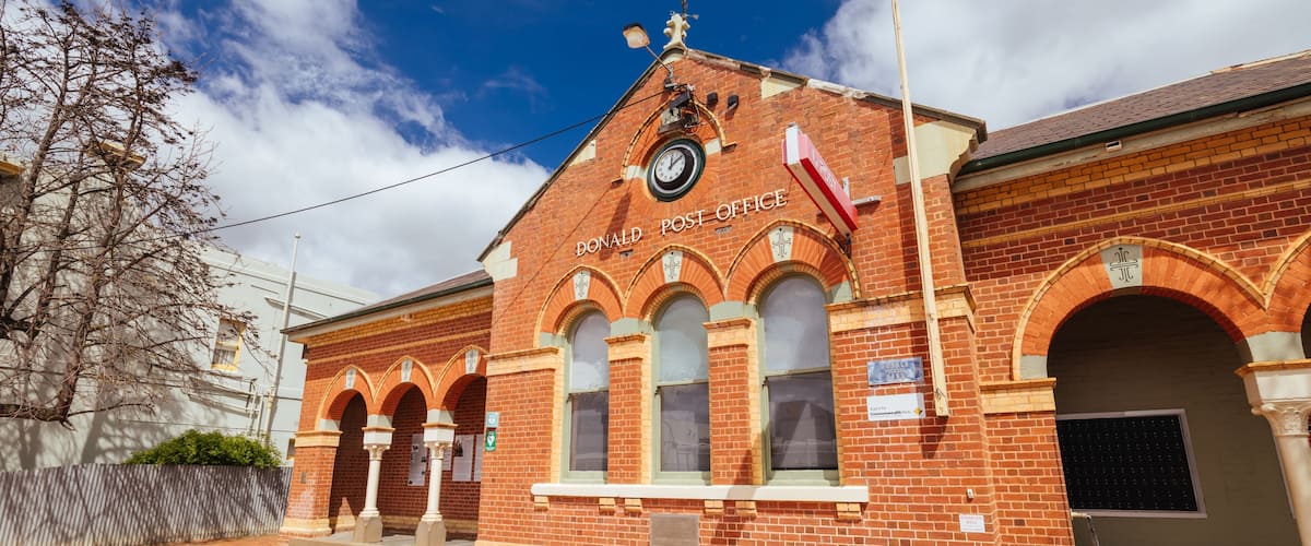 A brick building with arched windows and a clock, labeled "Donald Post Office."