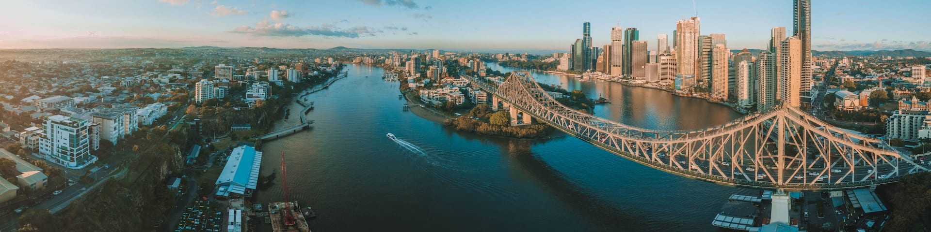 A cityscape with a prominent bridge spanning a river, surrounded by high-rise buildings and a clear sky.