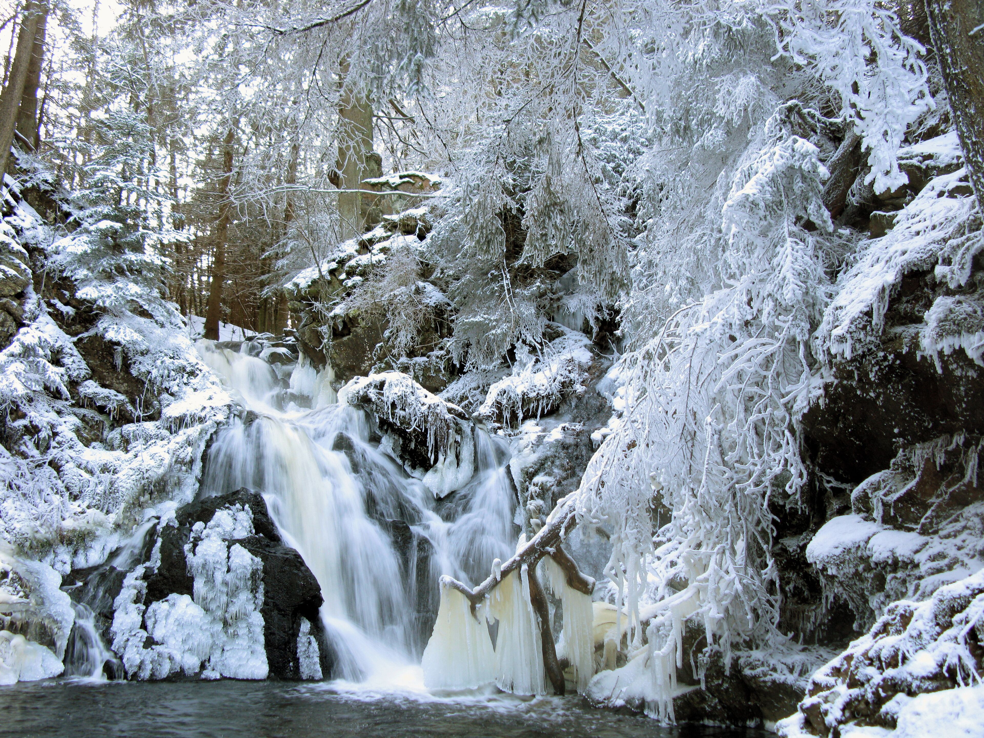 A snow-covered waterfall in a forest.