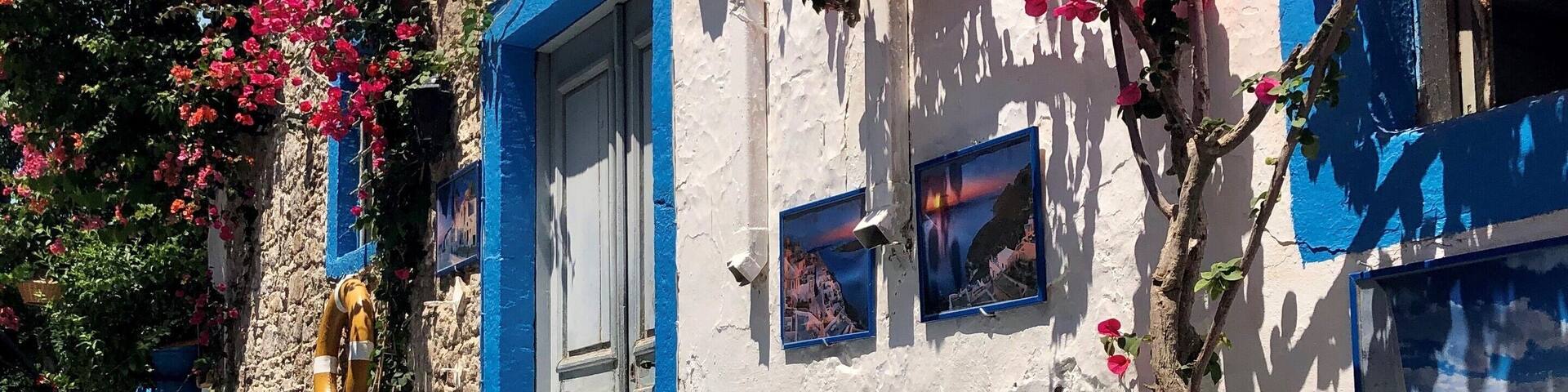 A child walking past a white building with blue shutters and pink bougainvillea flowers.