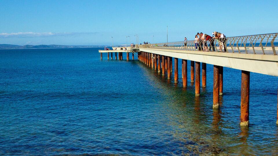 A pier extending into the water with people walking along it.
