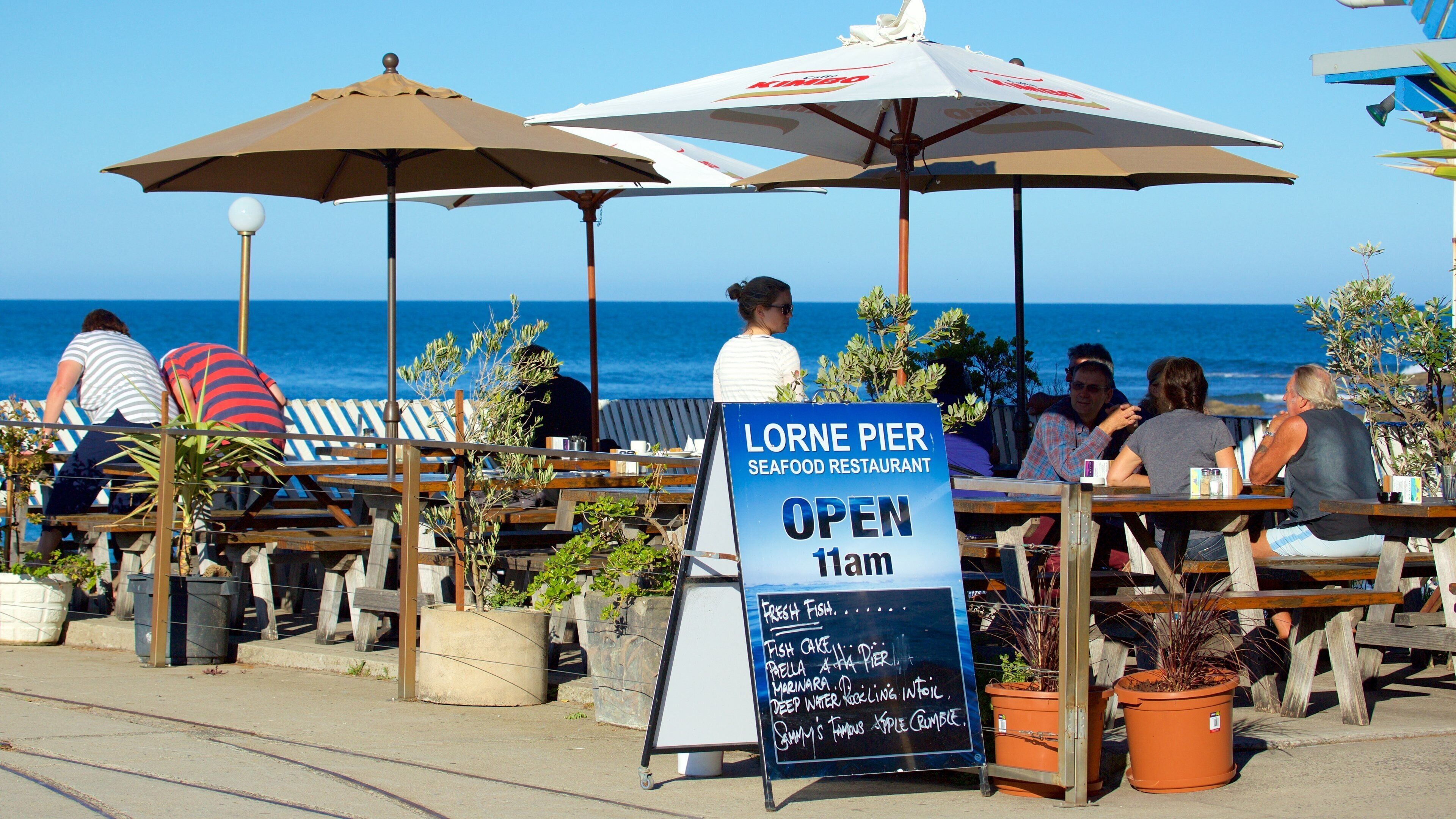 A seaside restaurant named Lorne Pier Seafood Restaurant with outdoor seating and umbrellas.