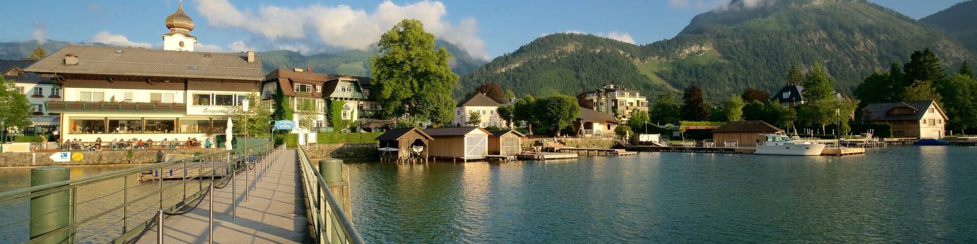 A lakeside town with buildings, a dock, and mountains in the background.