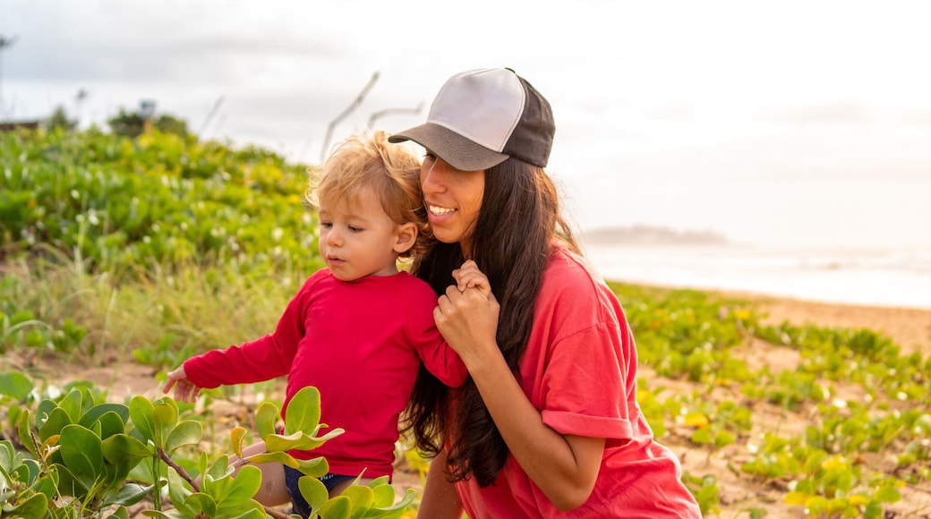 Mother and SON playing with vegetation at PRAIA D'ULÉ IN GUARAPARI ULE, ES, BRAZIL.