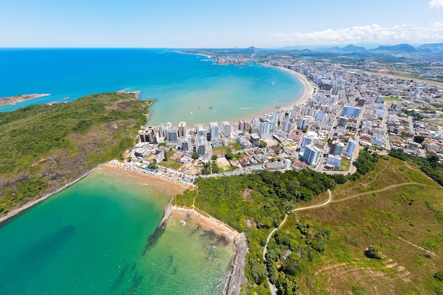 Imagem aérea de drone da Praia do Morro em um dia ensolarado, com pessoas passeando, praticando esportes e descansando ao sol. Cidade de Guarapari no Espírito Santo