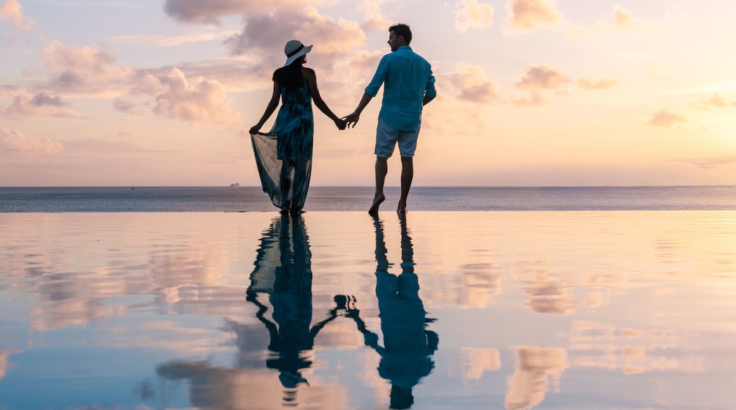 Couple walking hand in hand on a tranquil beach at sunset in Saint Lucia