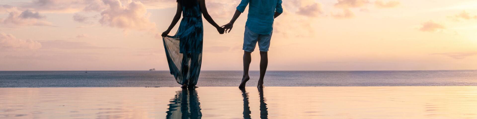 Couple walking hand in hand on a tranquil beach at sunset in Saint Lucia
