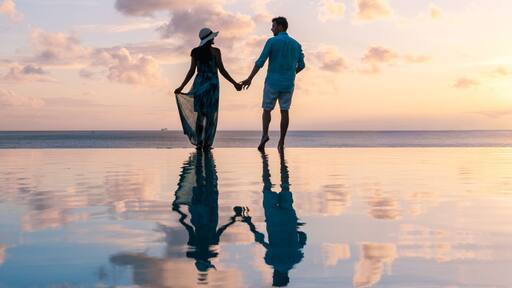 Couple walking hand in hand on a tranquil beach at sunset in Saint Lucia