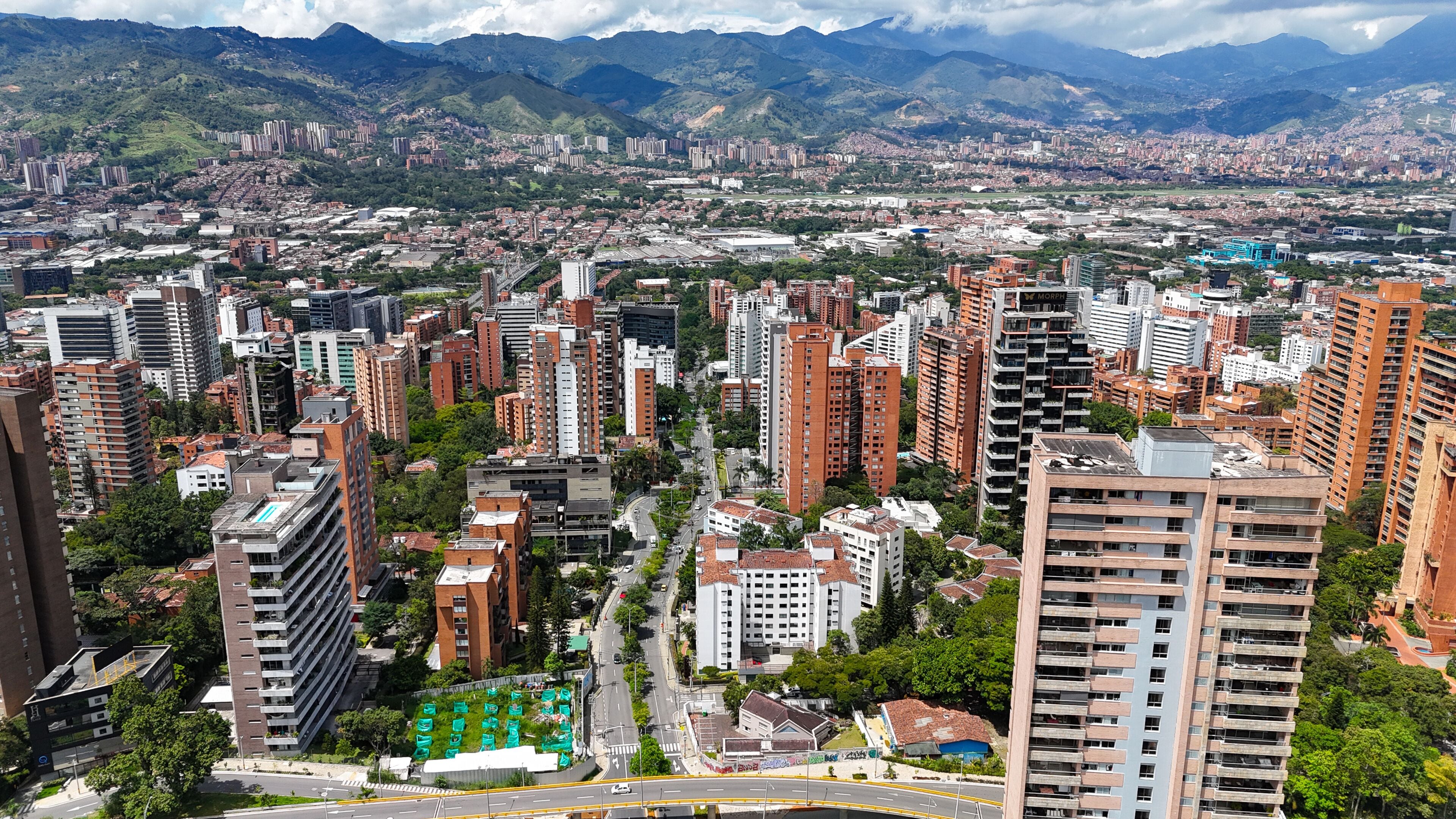 A cityscape with dense high-rise buildings, a river, and mountains in the background.