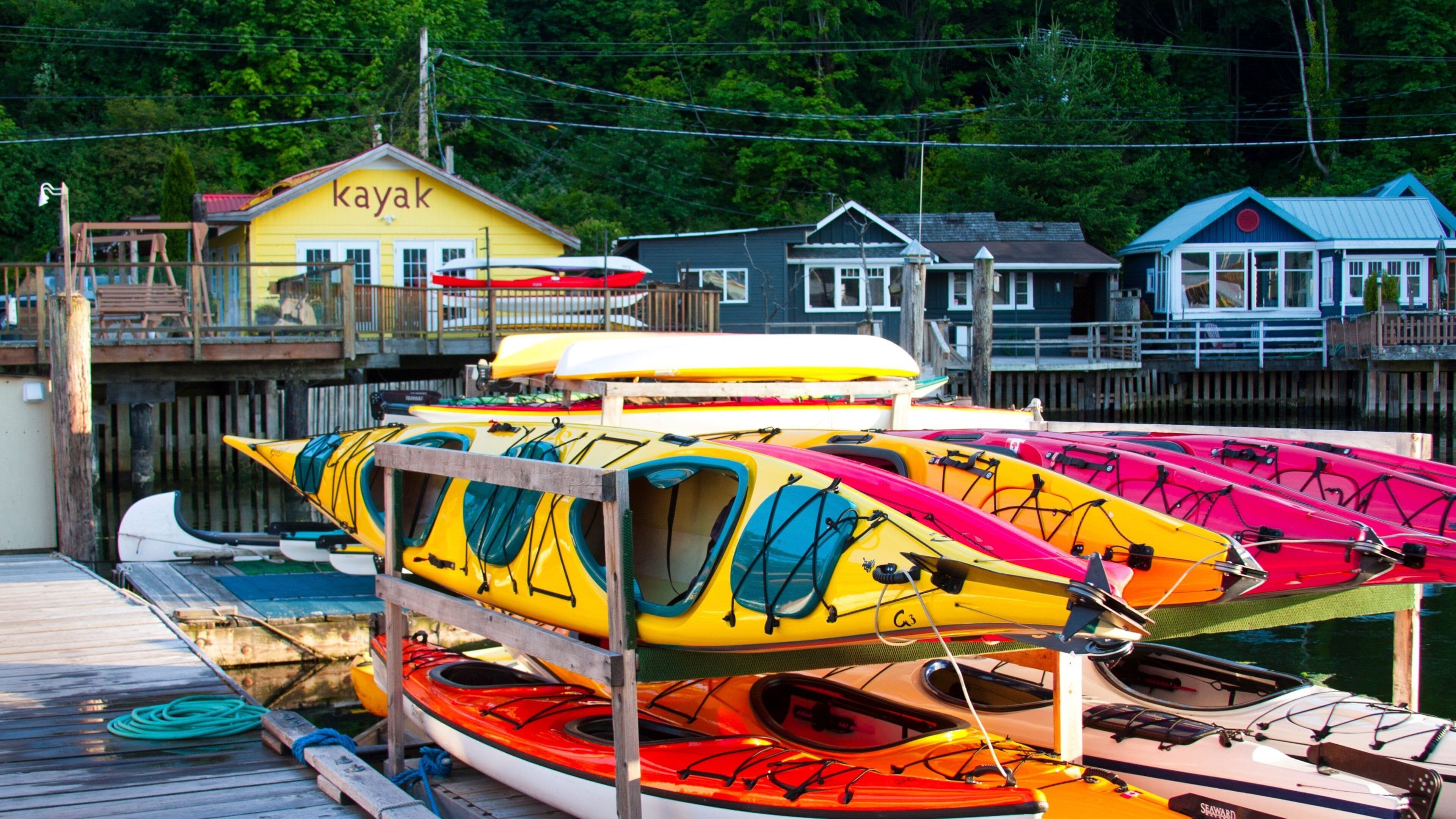 A dock with multiple kayaks and a building labeled "kayak" in the background.