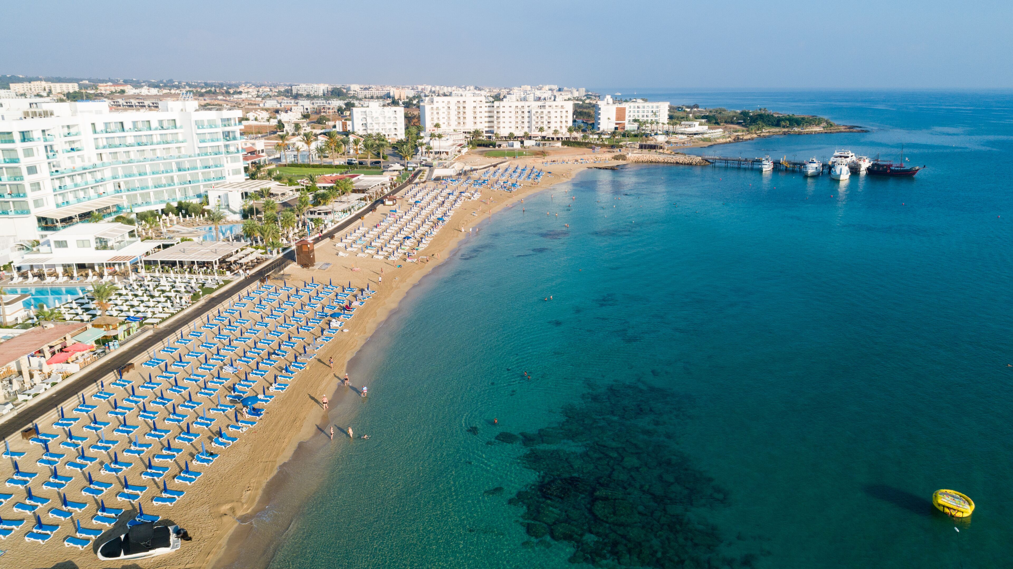 Aerial bird's eye view of Sunrise beach Fig tree, Protaras, Paralimni, Famagusta, Cyprus.The famous tourist attraction family bay with golden sand, boats, sunbeds, restaurants, water sports from above