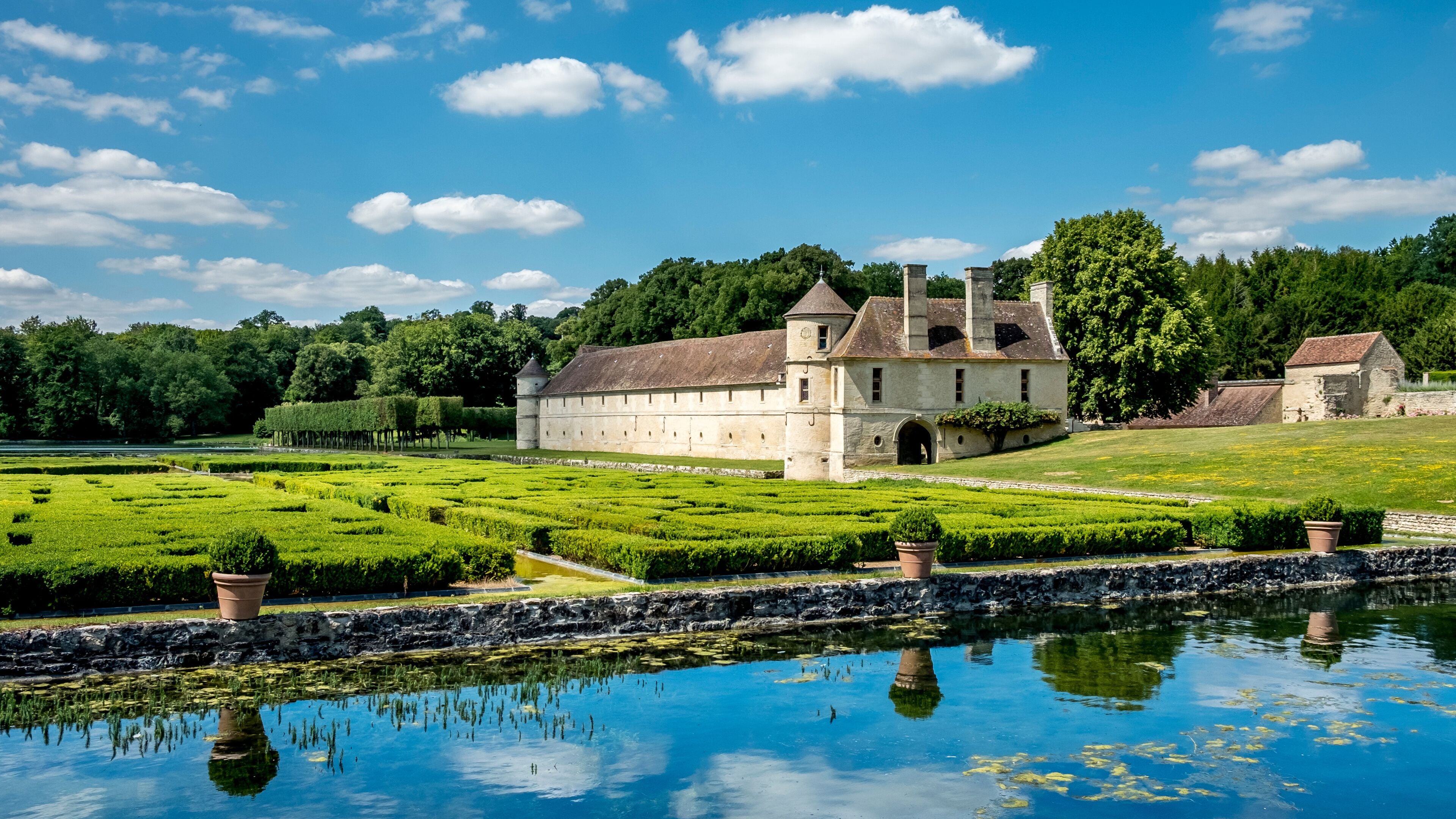 A historic building with a moat and lush gardens.
