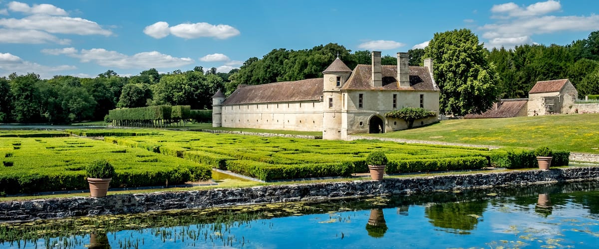 A historic building with a moat and lush gardens.