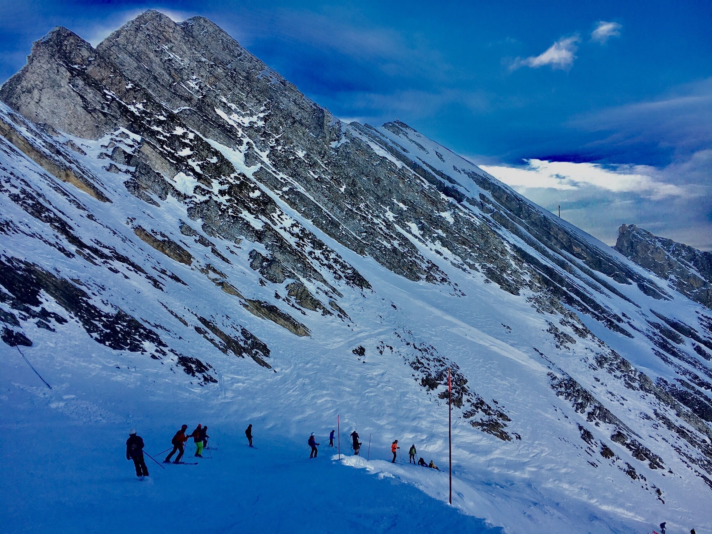 A snowy mountain slope with skiers and a clear sky.