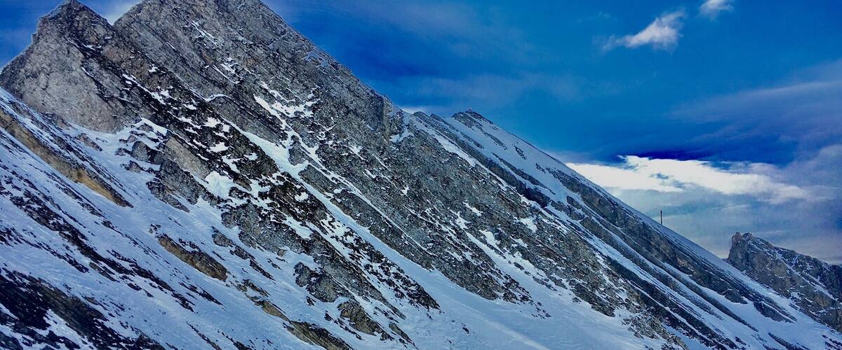 A snowy mountain slope with skiers and a clear sky.