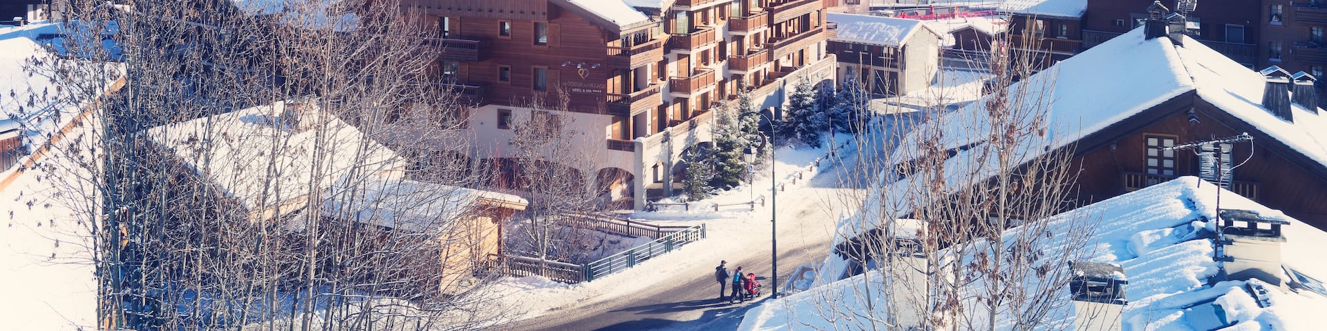 A snow-covered mountain town with wooden buildings, a church, and a ski lift.