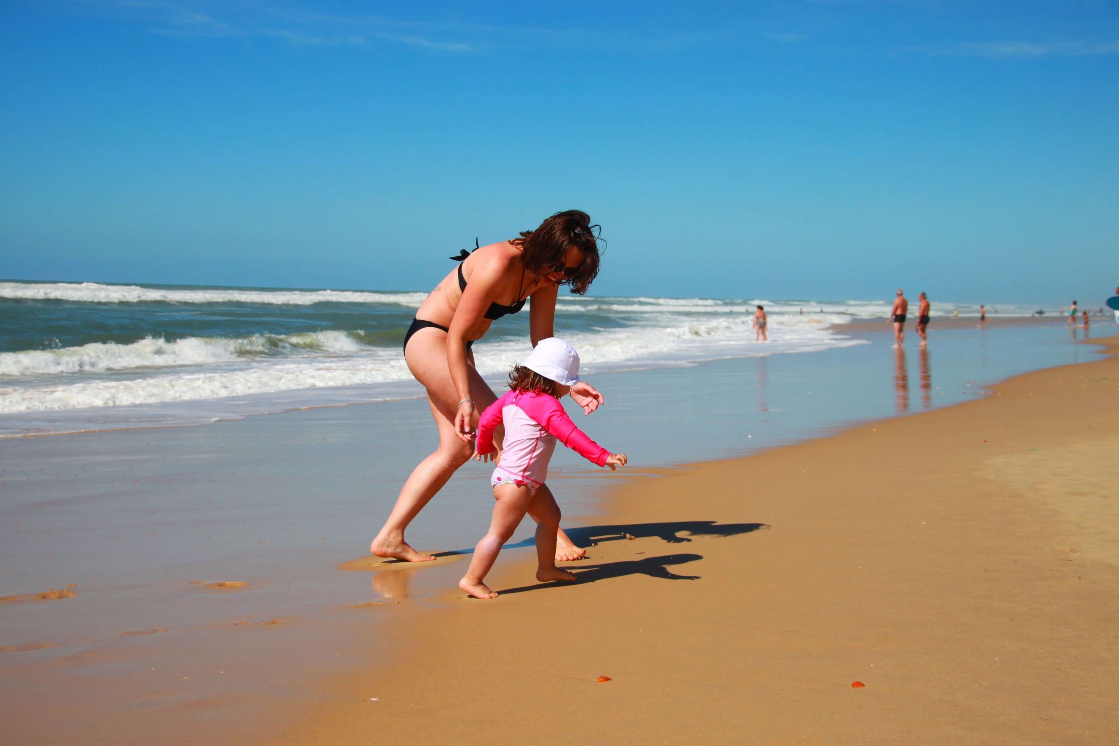 A beach with waves, people, and a clear sky.