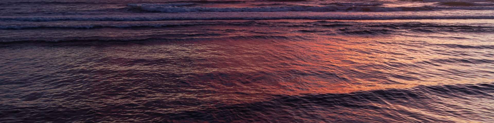 A sunset over the ocean with vibrant pink and purple clouds.
