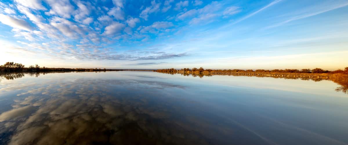 A calm river reflecting the sky and trees.
