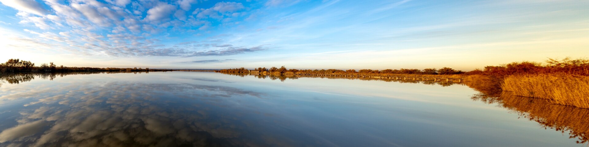 A calm river reflecting the sky and trees.