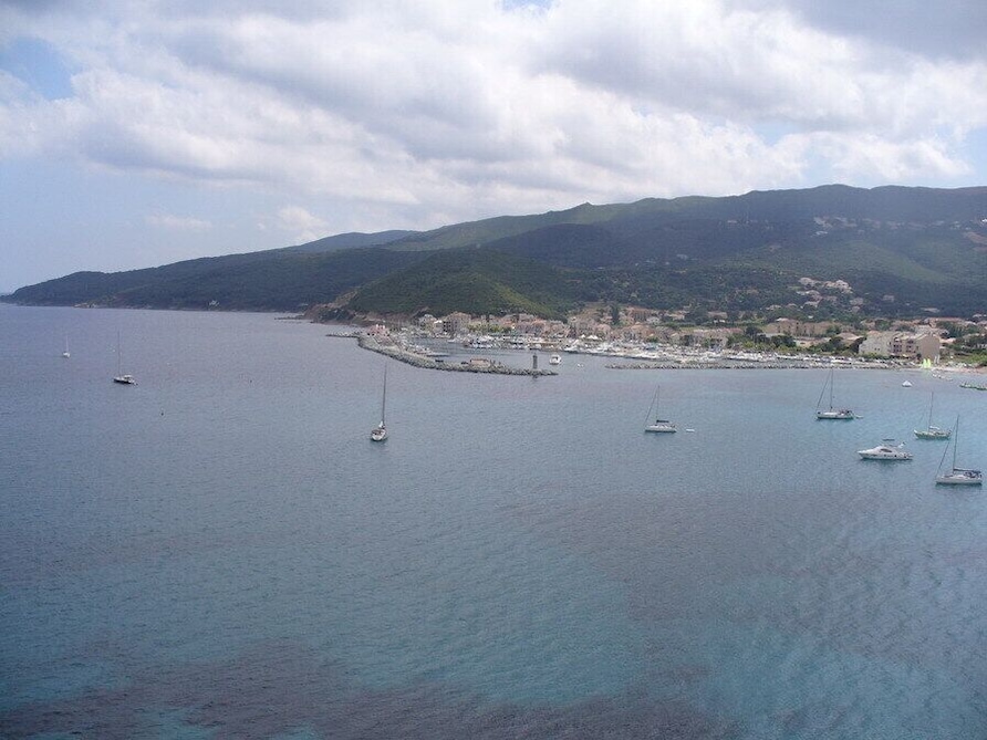 A coastal town with boats on the water and hills in the background.