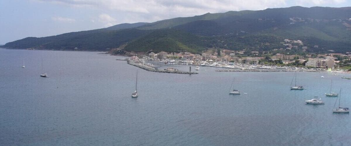 A coastal town with boats on the water and hills in the background.