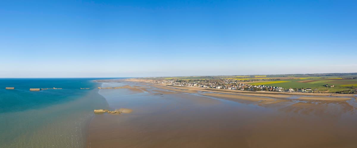 A coastal town with a beach, farmland, and a clear blue sky.