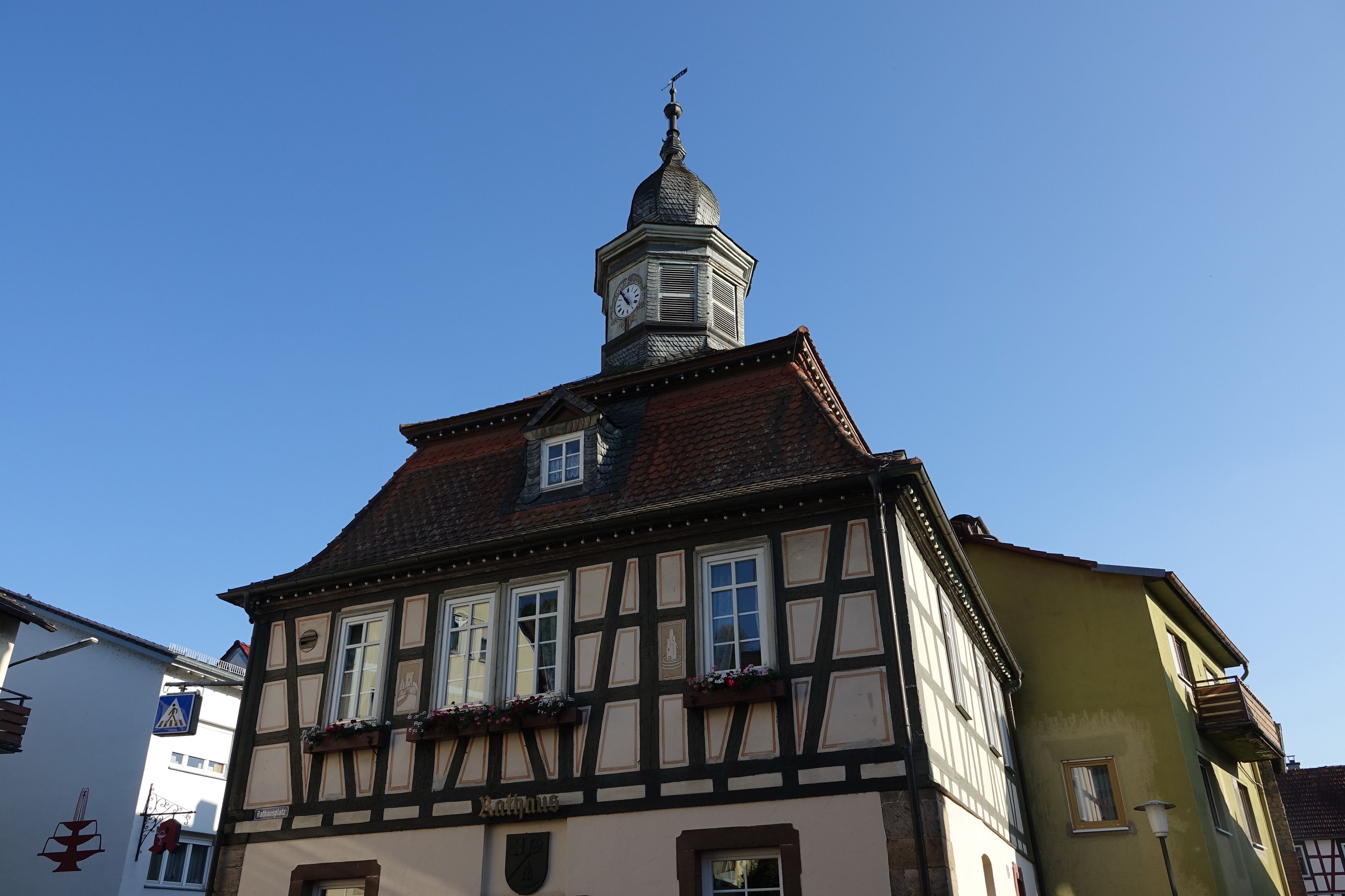 A half-timbered building with a clock tower and a sign reading 'Rathaus'.
