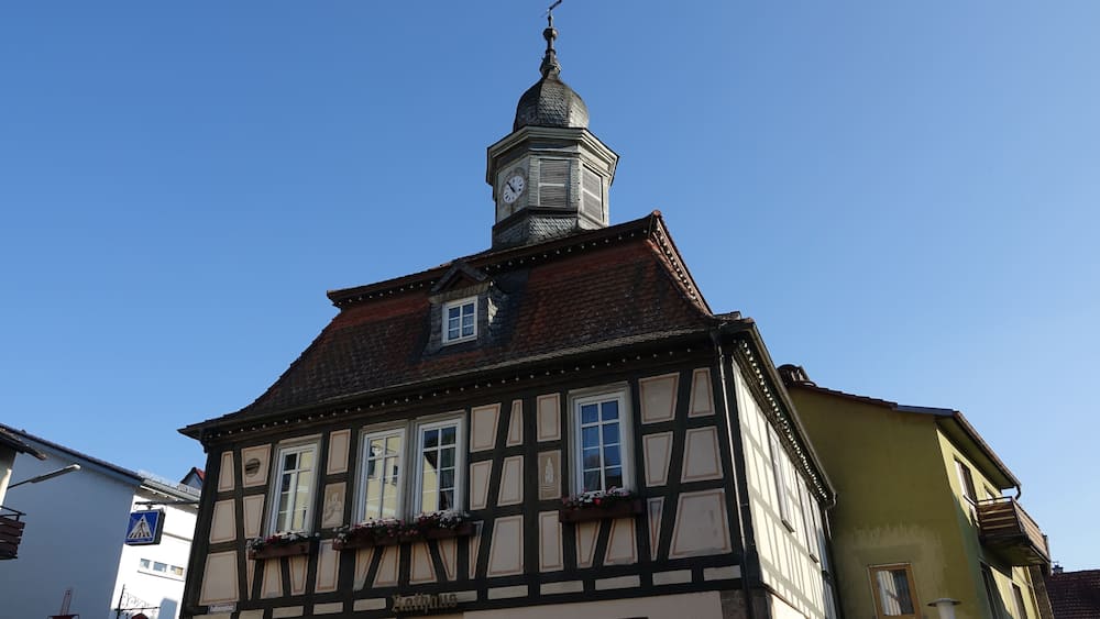 A half-timbered building with a clock tower and a sign reading 'Rathaus'.