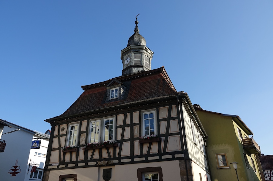 A half-timbered building with a clock tower and a sign reading 'Rathaus'.