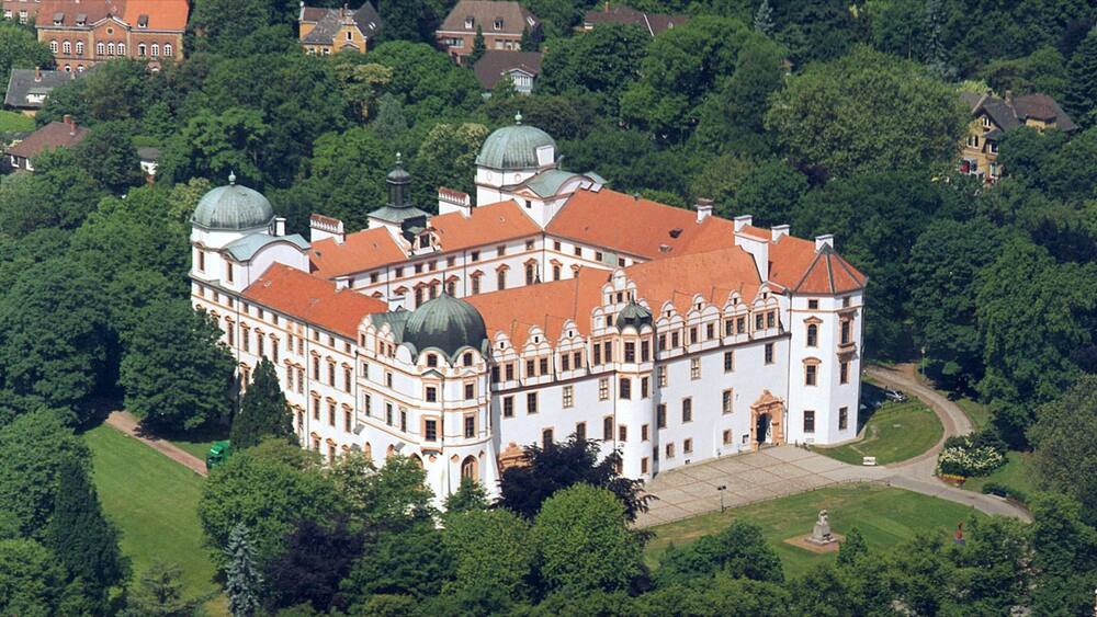 Ein schmuckes, weißes Gebäude mit roten Dächern, umgeben von üppiger Vegetation.