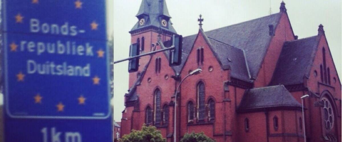 A church with a tall spire and a blue sign indicating 'Bonds-republiek Duitsland 1km'.