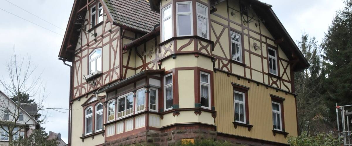 A traditional half-timbered house with a stone wall and a wooden fence.