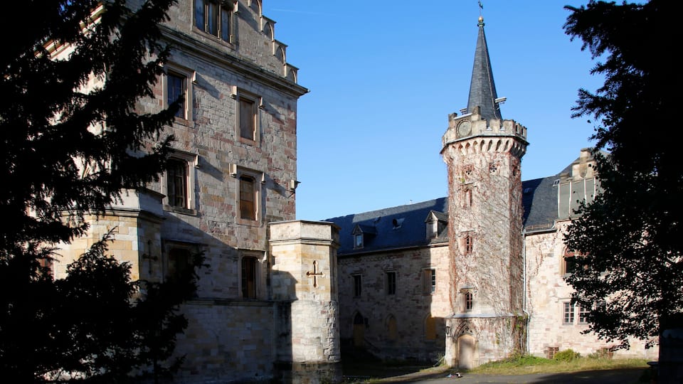A historic stone building with a prominent tower and a cross on its facade.