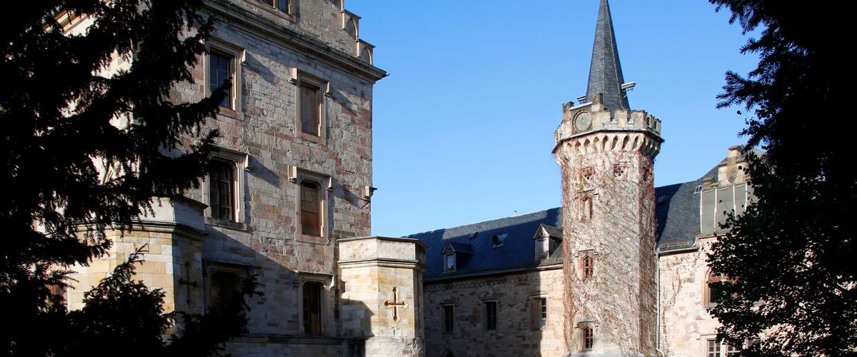 A historic stone building with a prominent tower and a cross on its facade.