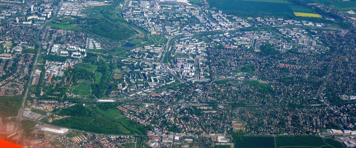 An aerial view of a city with dense urban areas, green spaces, and agricultural fields.