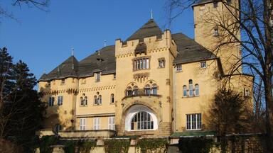 A large, yellow castle with a prominent arched entrance and multiple towers.