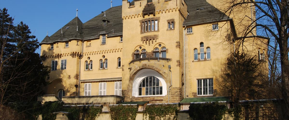 A large, yellow castle with a prominent arched entrance and multiple towers.