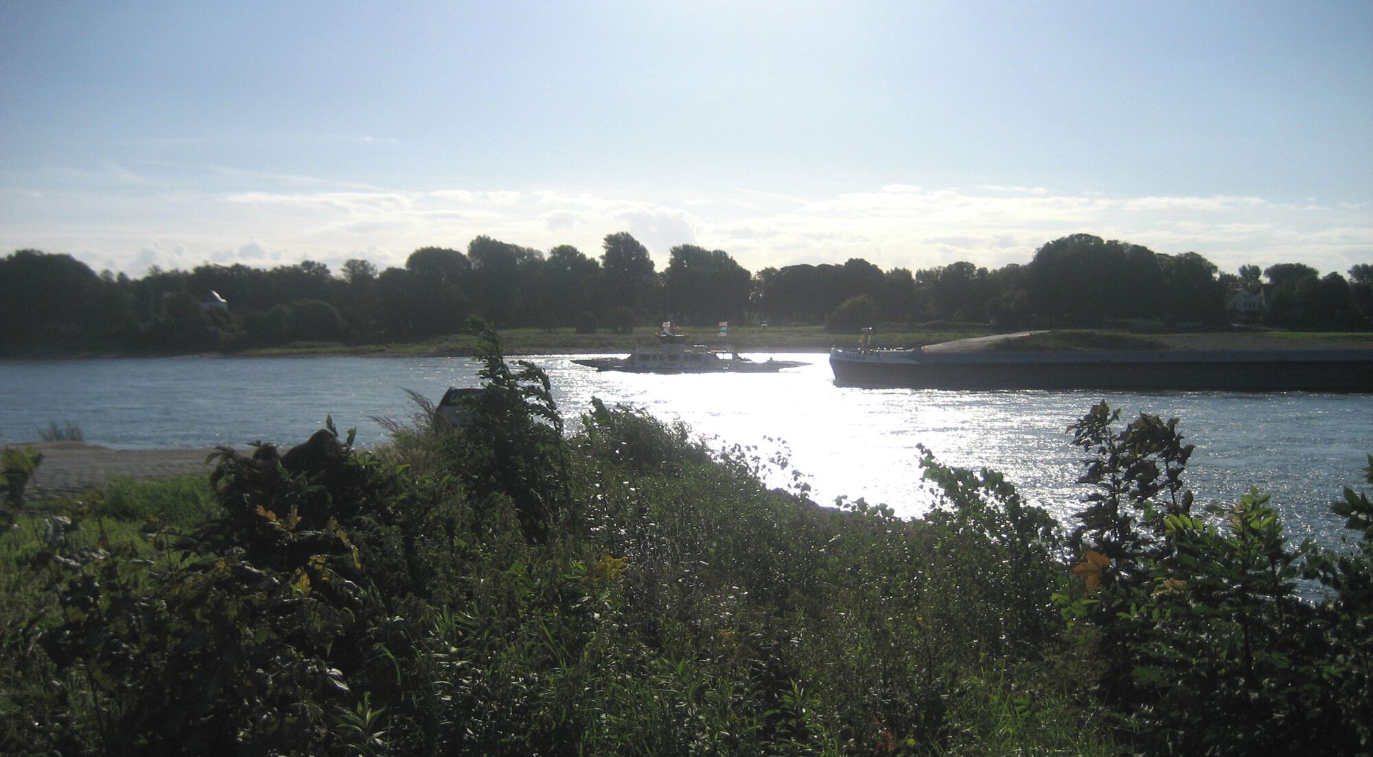 A river with a boat, surrounded by greenery and trees.