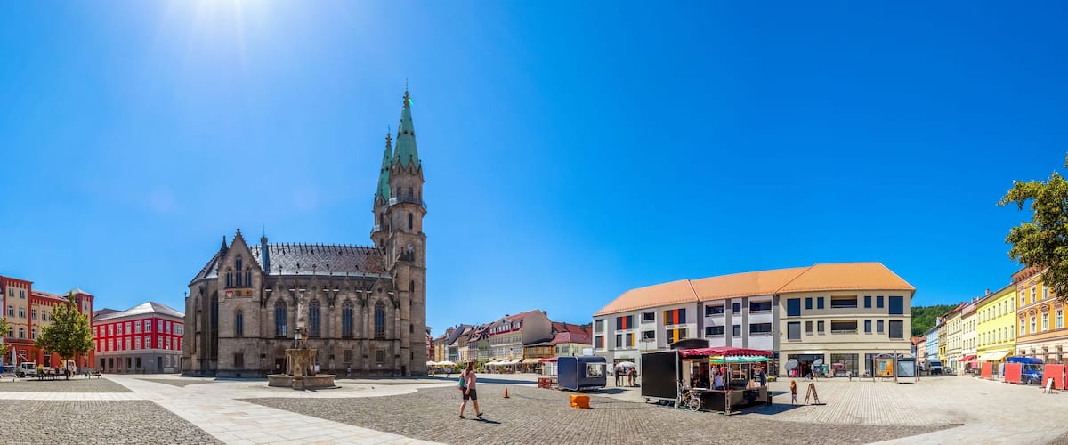 A historic church with a tall spire, cobblestone square, and colorful buildings.