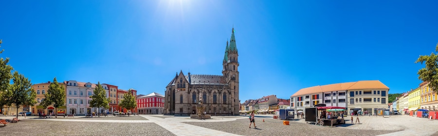 A historic church with a tall spire, cobblestone square, and colorful buildings.