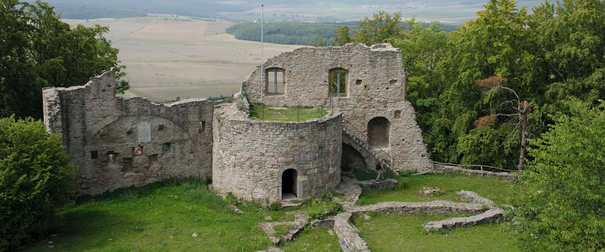 A stone ruin with a grassy foreground and a distant view of hills and fields.