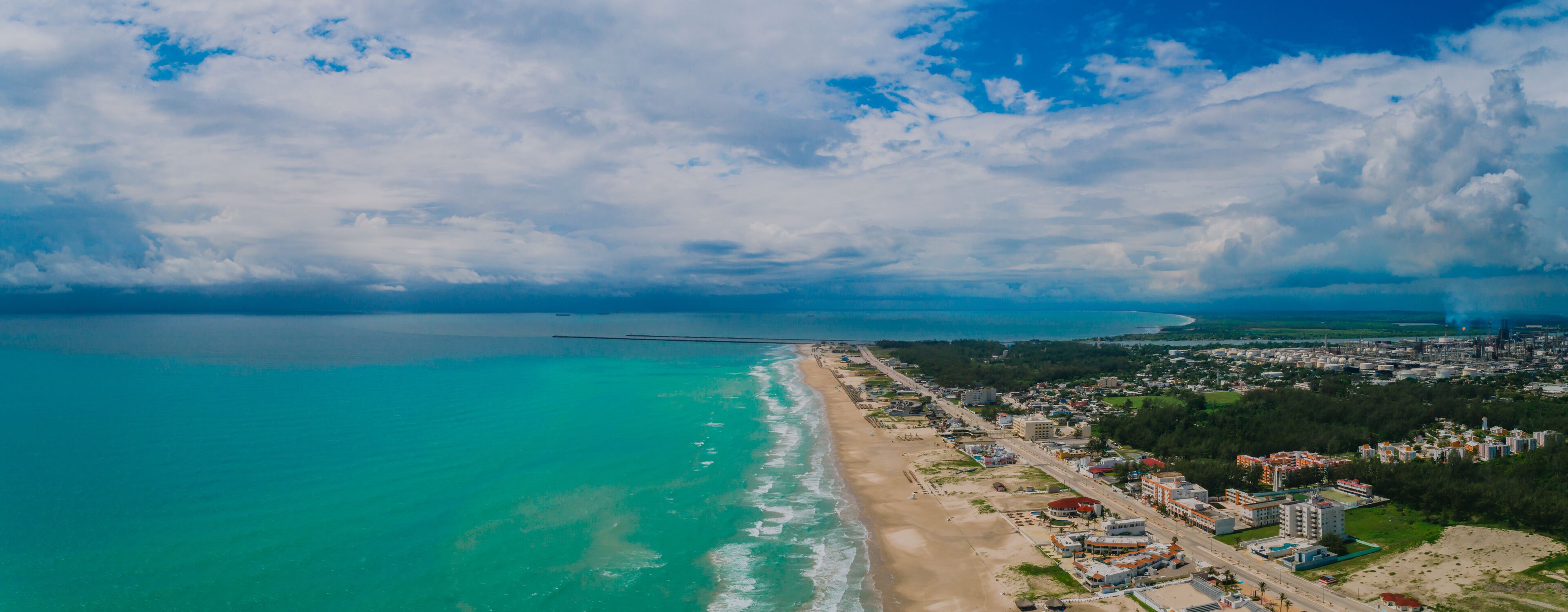 A coastal city with a beach, a bridge, and industrial buildings.