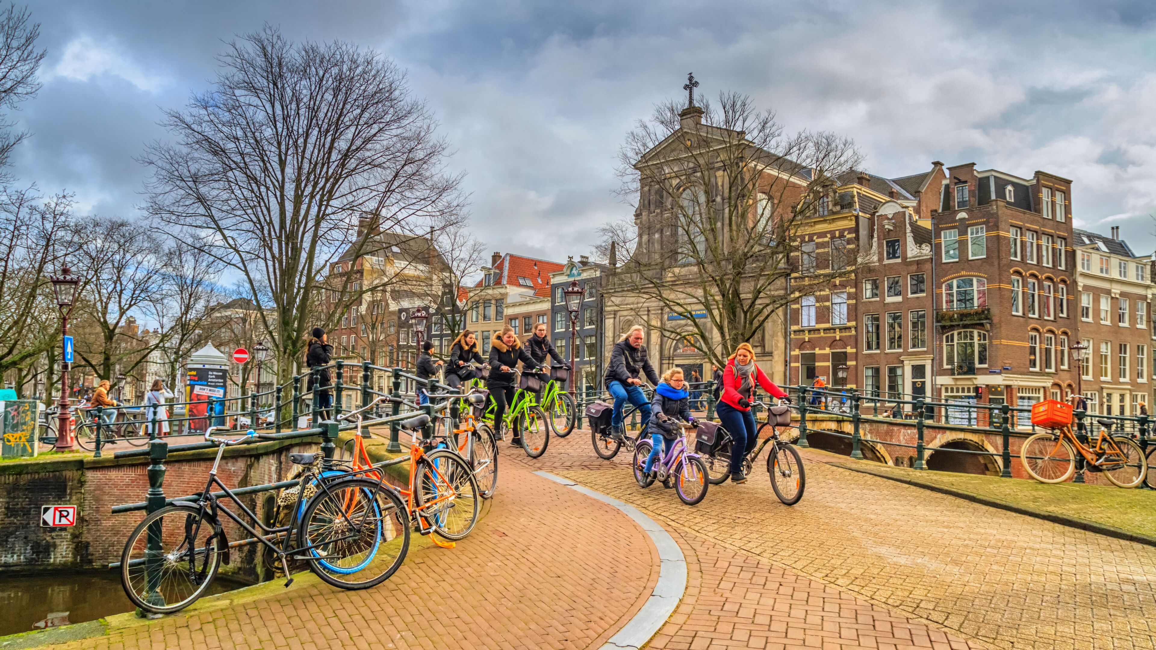 Cityscape on a sunny winter day - view on the group of cyclists in the historic center of Amsterdam, The Netherlands