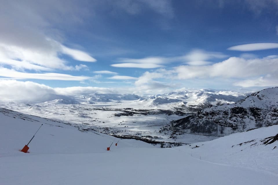 A snow-covered mountain landscape with a ski slope and a clear sky.