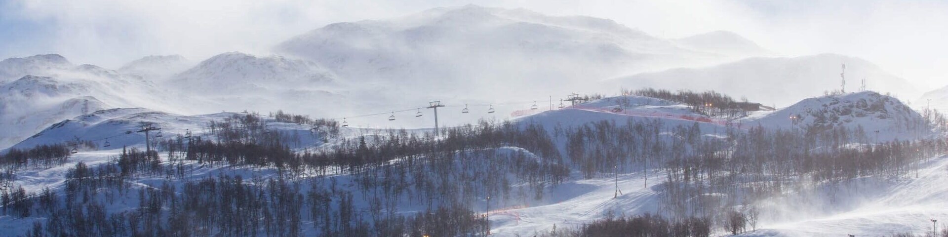 A snow-covered mountain landscape with ski lifts and a forested area.
