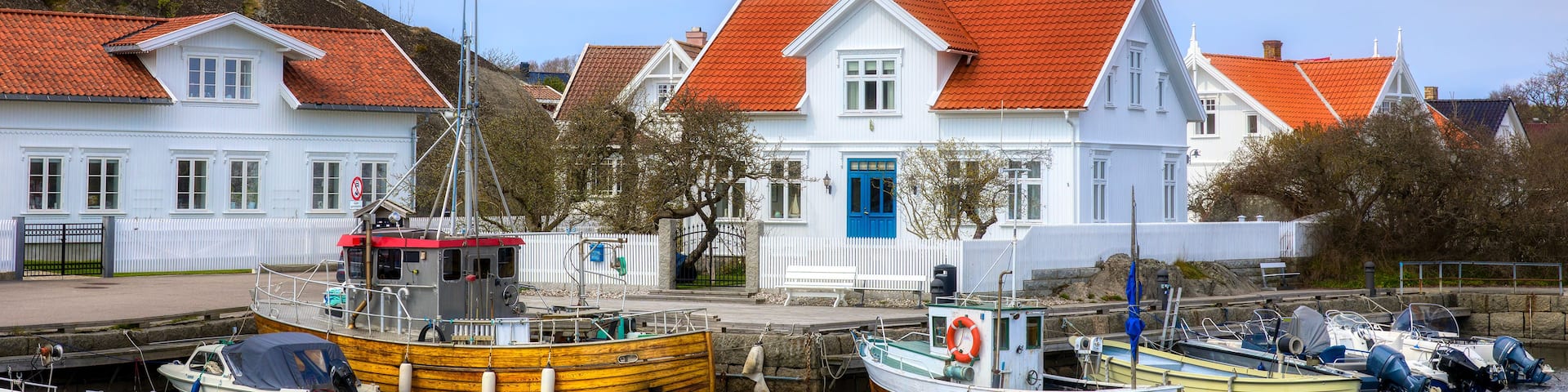 A harbor with several boats docked, a white building with a red roof, and a blue door.